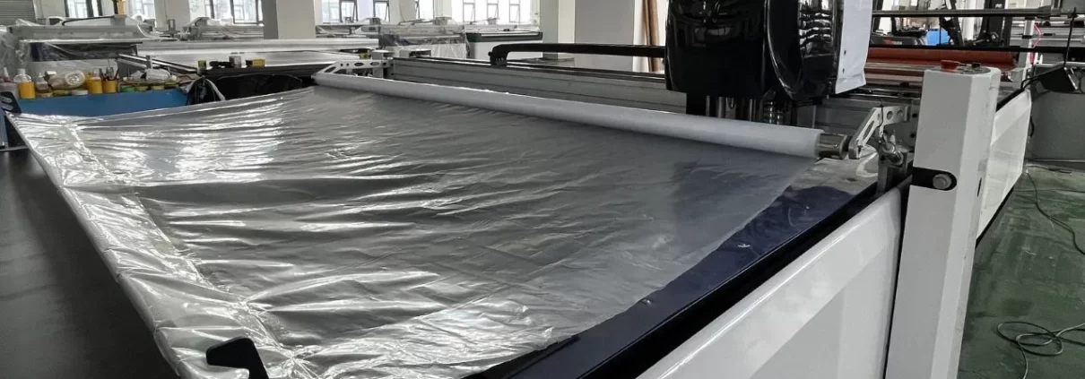 automatic fabric cutting machine plastic film covering fabric 1 1210x423 - AUTOMATISCHE STOFFSCHNEIDEMASCHINE